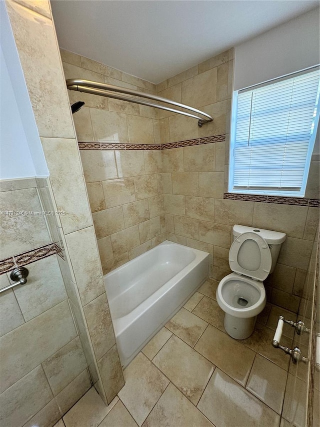 bathroom featuring tiled shower / bath, tile walls, tile patterned floors, and toilet