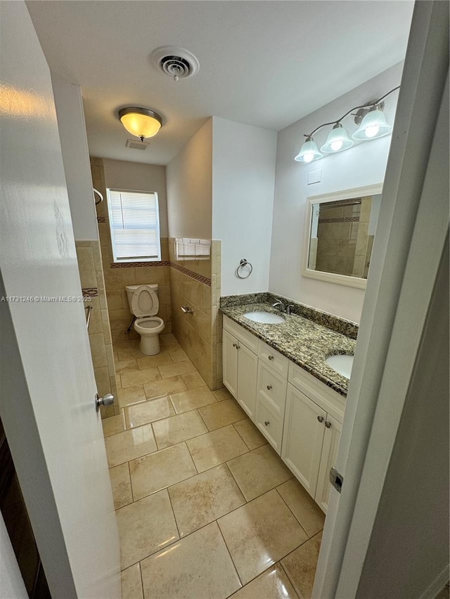 bathroom with vanity, toilet, tile patterned flooring, and tile walls