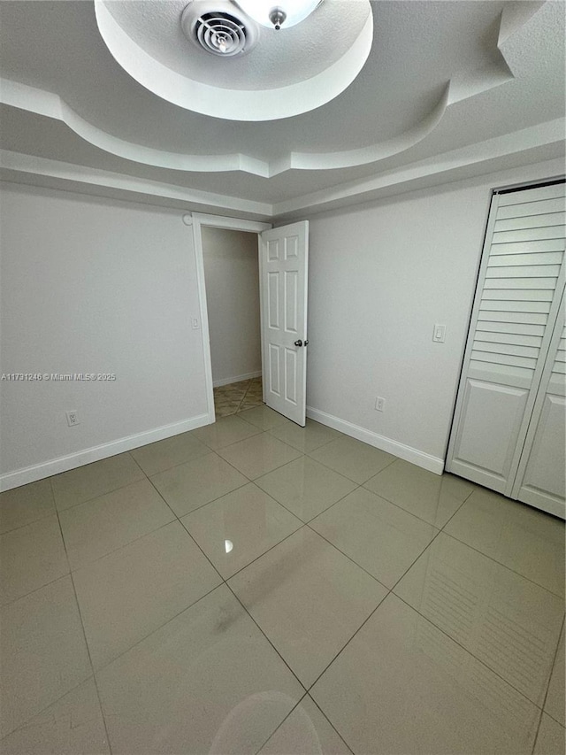 unfurnished bedroom featuring tile patterned floors and a tray ceiling