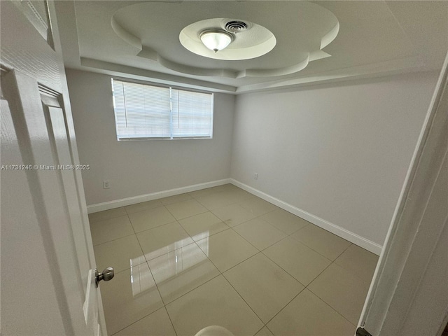 tiled spare room with a raised ceiling