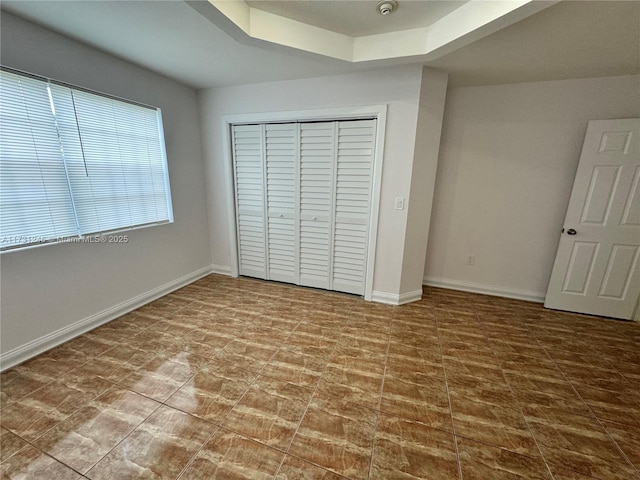 unfurnished bedroom with a closet and a raised ceiling