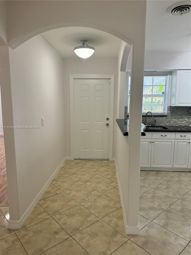 doorway featuring sink and light tile patterned floors