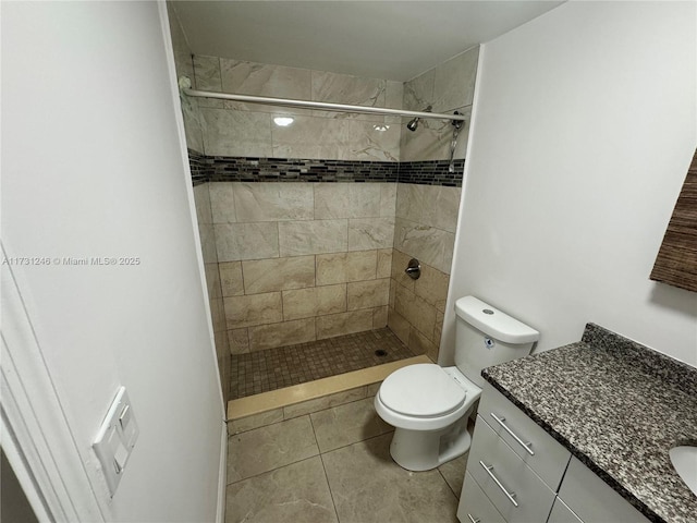 bathroom featuring tile patterned flooring, vanity, tiled shower, and toilet