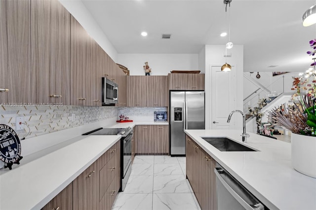 kitchen featuring pendant lighting, sink, decorative backsplash, and stainless steel appliances