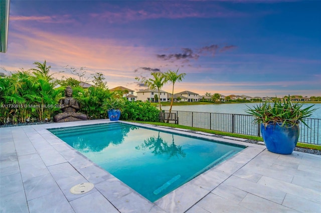 pool at dusk featuring a water view and a patio area