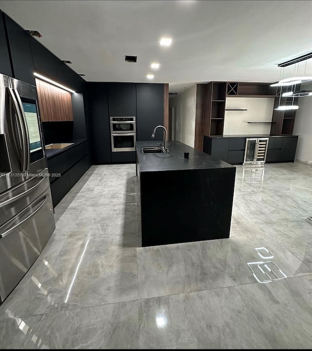 kitchen featuring an island with sink, sink, and stainless steel fridge with ice dispenser