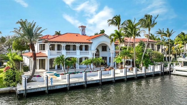 back of property with a patio, a balcony, and a water view