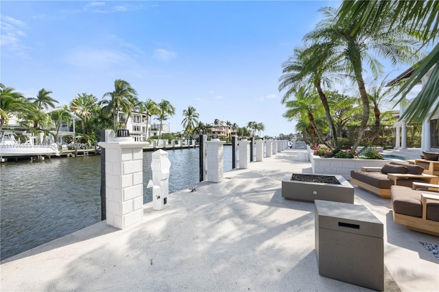 exterior space featuring a water view, an outdoor fire pit, and a dock