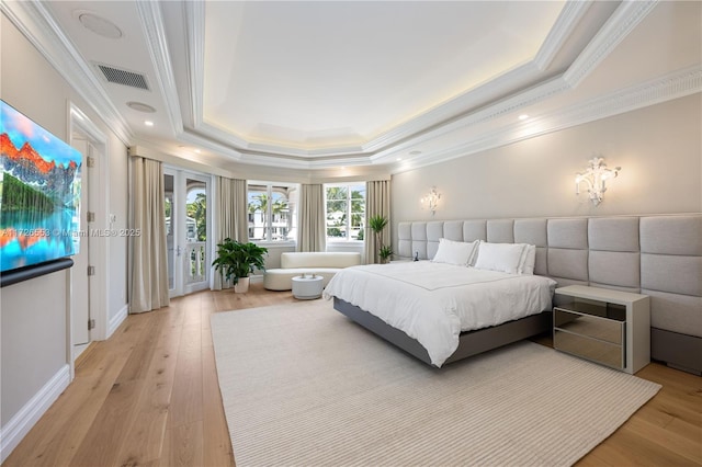 bedroom featuring crown molding, access to exterior, a raised ceiling, and light wood-type flooring