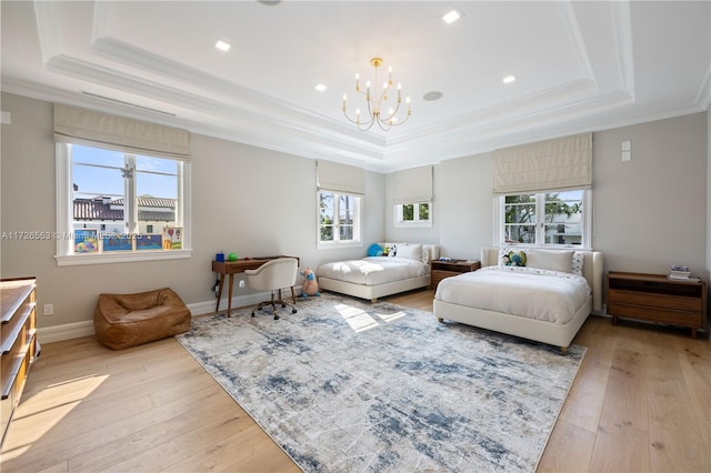 bedroom with light wood-type flooring and a tray ceiling