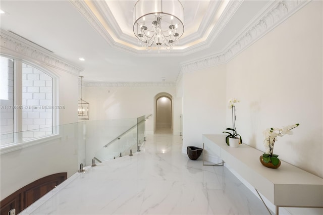 corridor featuring crown molding, a notable chandelier, and a tray ceiling