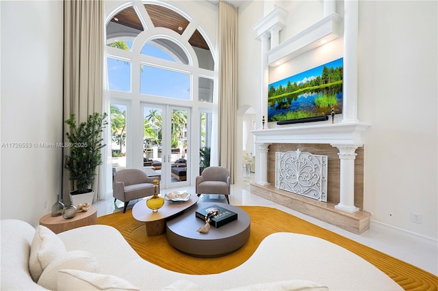 living room with a premium fireplace, a towering ceiling, and french doors