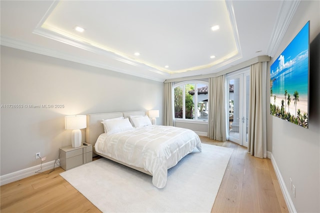 bedroom featuring ornamental molding, light hardwood / wood-style floors, and a tray ceiling