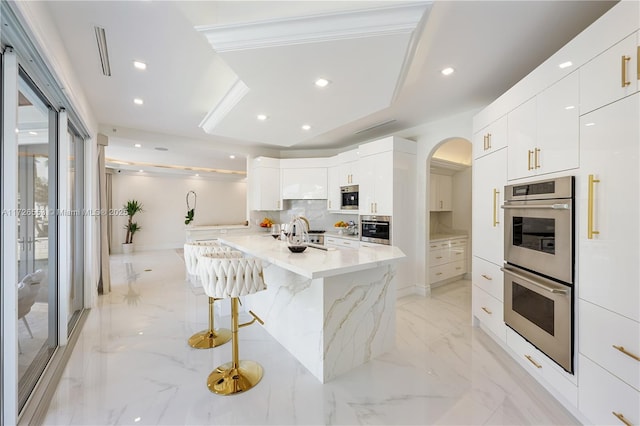 kitchen with stainless steel double oven, a kitchen bar, kitchen peninsula, and white cabinets