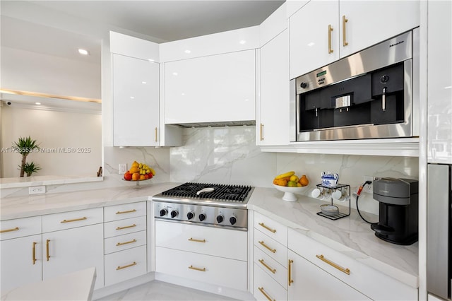 kitchen featuring stainless steel appliances, white cabinetry, light stone countertops, and tasteful backsplash