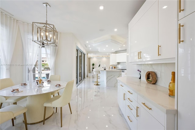 kitchen featuring a spacious island, white cabinetry, light stone counters, decorative light fixtures, and decorative backsplash