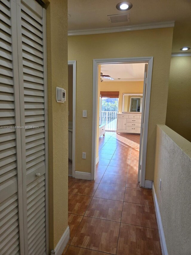 corridor featuring ornamental molding and dark tile patterned floors