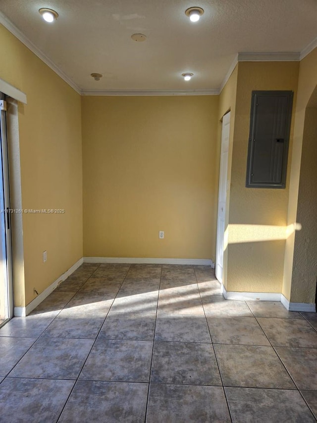 empty room with tile patterned flooring, crown molding, and electric panel