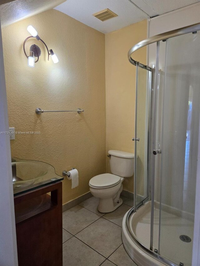 bathroom featuring vanity, toilet, a shower with door, and tile patterned flooring