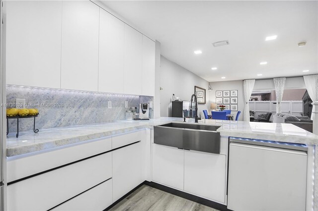 kitchen featuring sink, appliances with stainless steel finishes, white cabinets, light stone countertops, and backsplash