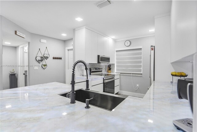 kitchen with sink, white cabinetry, light stone counters, light hardwood / wood-style floors, and washing machine and clothes dryer