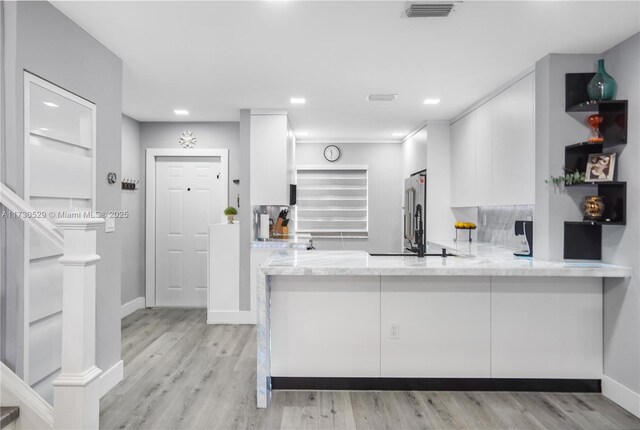 kitchen featuring sink, white cabinetry, light hardwood / wood-style flooring, kitchen peninsula, and dishwasher