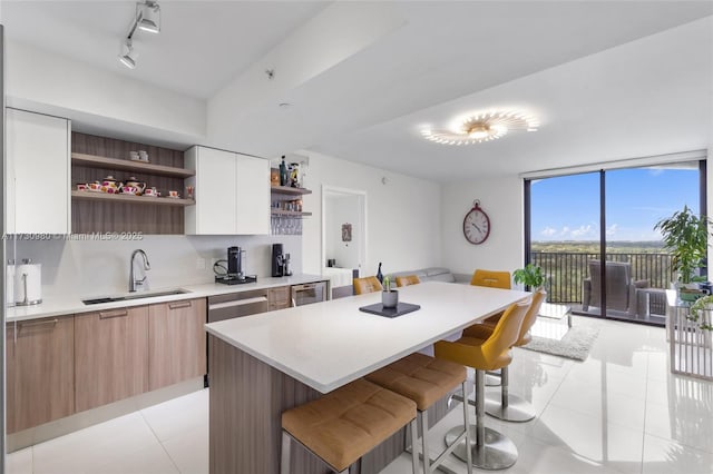 kitchen featuring sink, a breakfast bar area, white cabinetry, a center island, and expansive windows