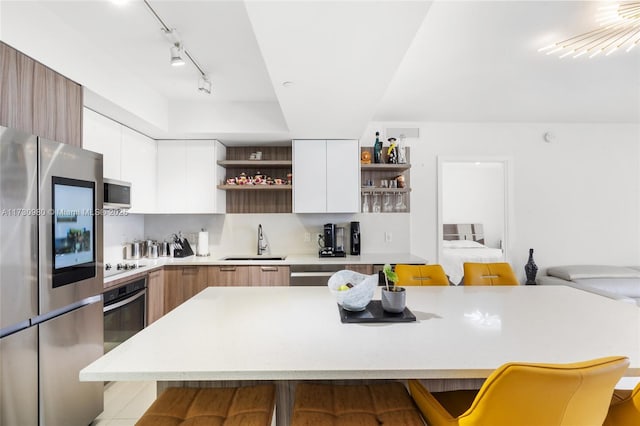 kitchen with appliances with stainless steel finishes, a breakfast bar, sink, and white cabinets