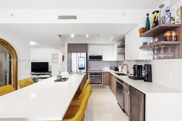 kitchen featuring wine cooler, sink, a center island, appliances with stainless steel finishes, and white cabinets