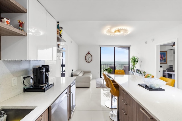 kitchen with light tile patterned floors, backsplash, dishwasher, and white cabinets