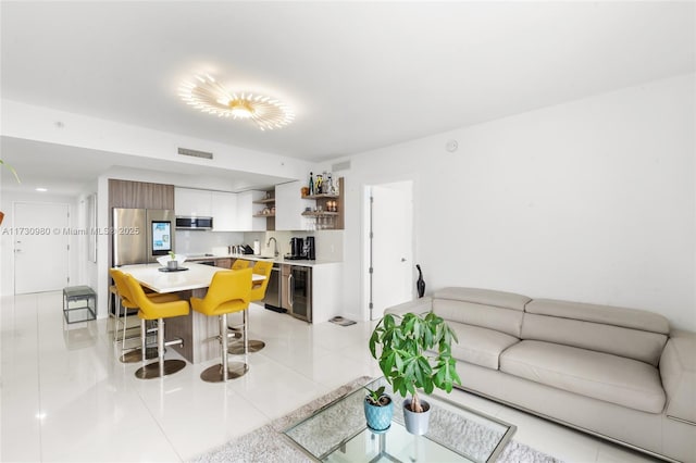 living room with wine cooler, sink, and light tile patterned floors