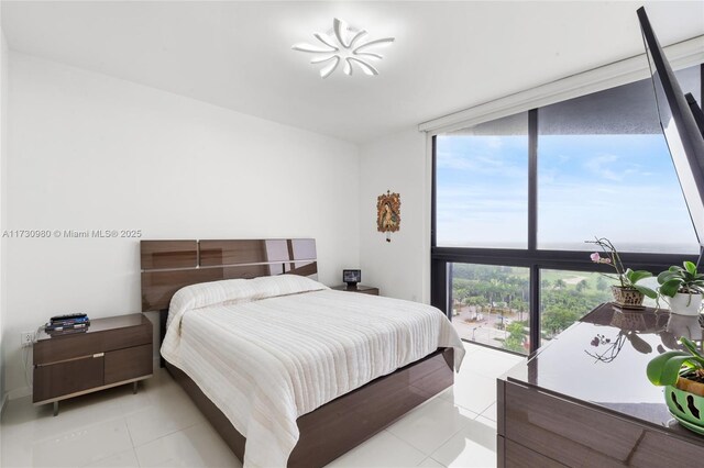 bedroom featuring multiple windows, expansive windows, and light tile patterned floors