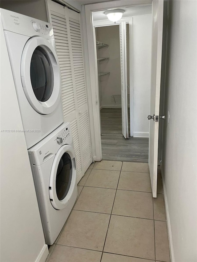 laundry room featuring stacked washer and dryer and light tile patterned floors