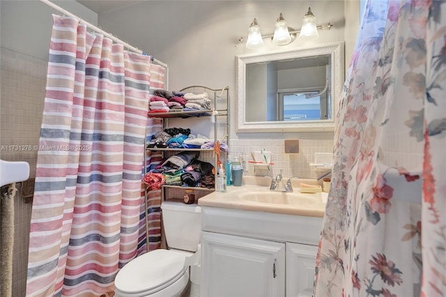 bathroom featuring vanity, toilet, curtained shower, and decorative backsplash