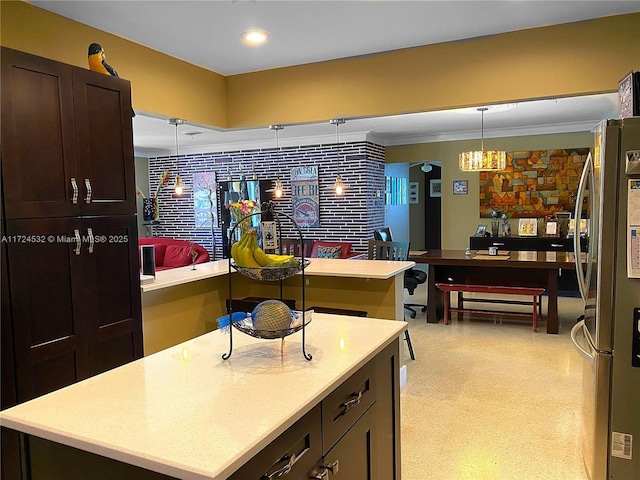 kitchen with pendant lighting, dark brown cabinets, a kitchen island, and stainless steel refrigerator