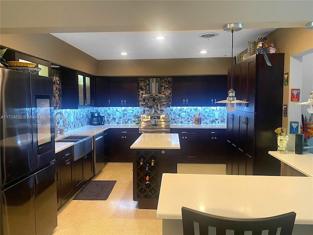 kitchen with pendant lighting, backsplash, stainless steel appliances, and wall chimney exhaust hood