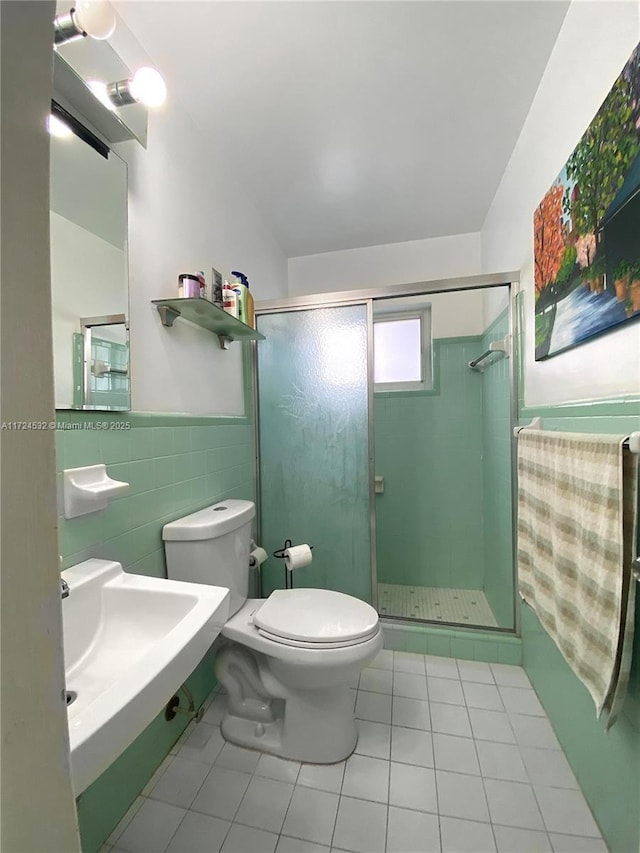 bathroom featuring tile walls, tile patterned flooring, a shower with door, and toilet