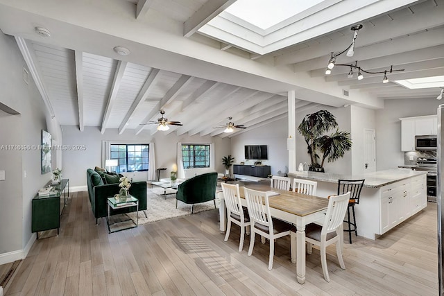 dining space featuring lofted ceiling with skylight and light hardwood / wood-style floors