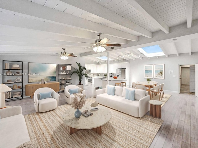 living room with a ceiling fan, vaulted ceiling with skylight, light wood-style flooring, and baseboards