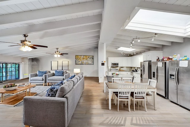 living room with lofted ceiling with beams, rail lighting, and light wood-type flooring