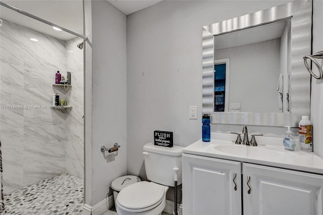 bathroom with vanity, tiled shower, and toilet