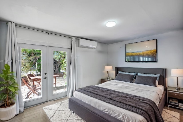 bedroom featuring light hardwood / wood-style flooring, access to exterior, a wall unit AC, and french doors