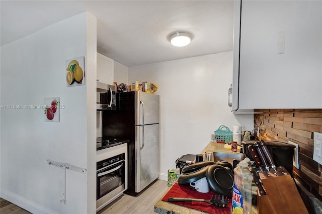 kitchen featuring backsplash, light hardwood / wood-style flooring, stainless steel appliances, and white cabinets