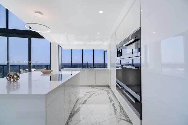 18555 Collins Ave Unit 4203, Sunny Isles Beach, FL 33160 - kitchen with modern cabinets, white cabinets, black electric stovetop, wall oven, and hanging light fixtures