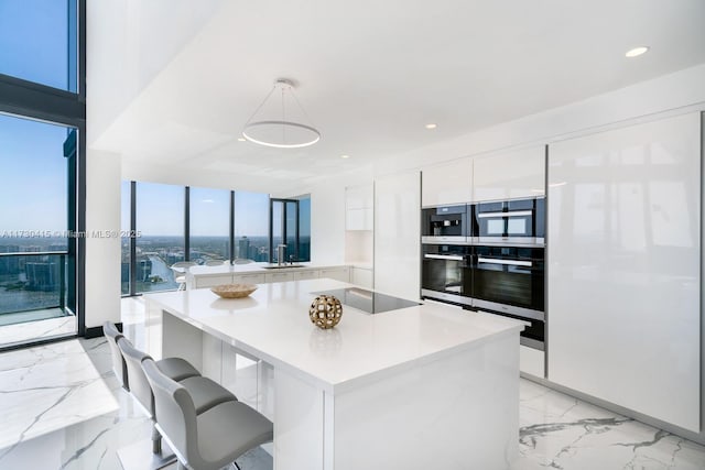 18555 Collins Ave Unit 4203, Sunny Isles Beach, FL 33160 - kitchen featuring modern cabinets, white cabinetry, black appliances, light marble finish flooring, and light countertops