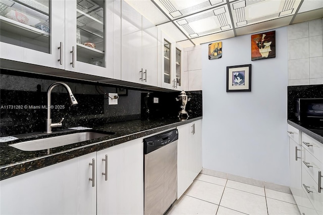 kitchen with white cabinetry, dishwasher, sink, dark stone counters, and decorative backsplash
