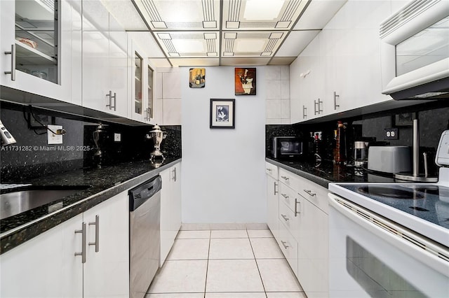 kitchen featuring white cabinetry, dark stone countertops, light tile patterned floors, white appliances, and decorative backsplash