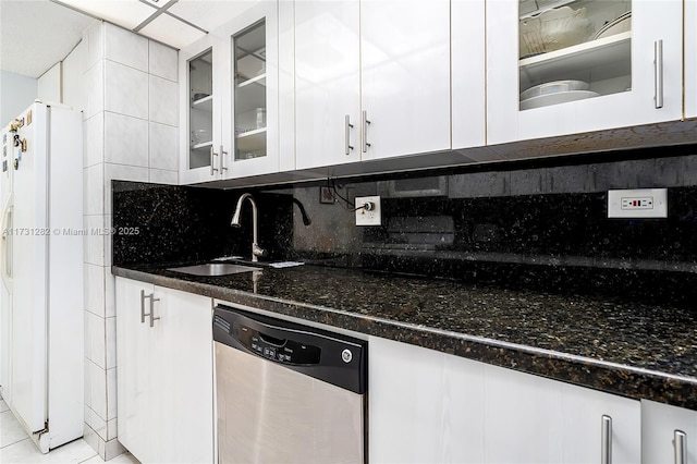 kitchen with sink, dark stone countertops, white refrigerator with ice dispenser, white cabinets, and stainless steel dishwasher