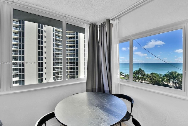 dining area featuring a water view and a textured ceiling