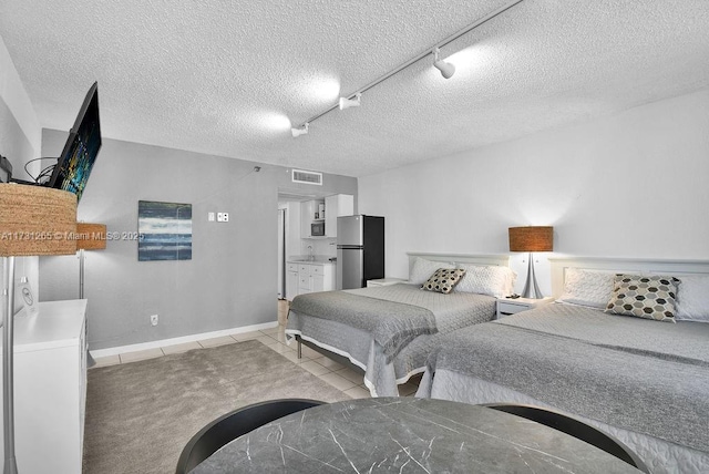 bedroom featuring rail lighting, light tile patterned floors, stainless steel fridge, and a textured ceiling